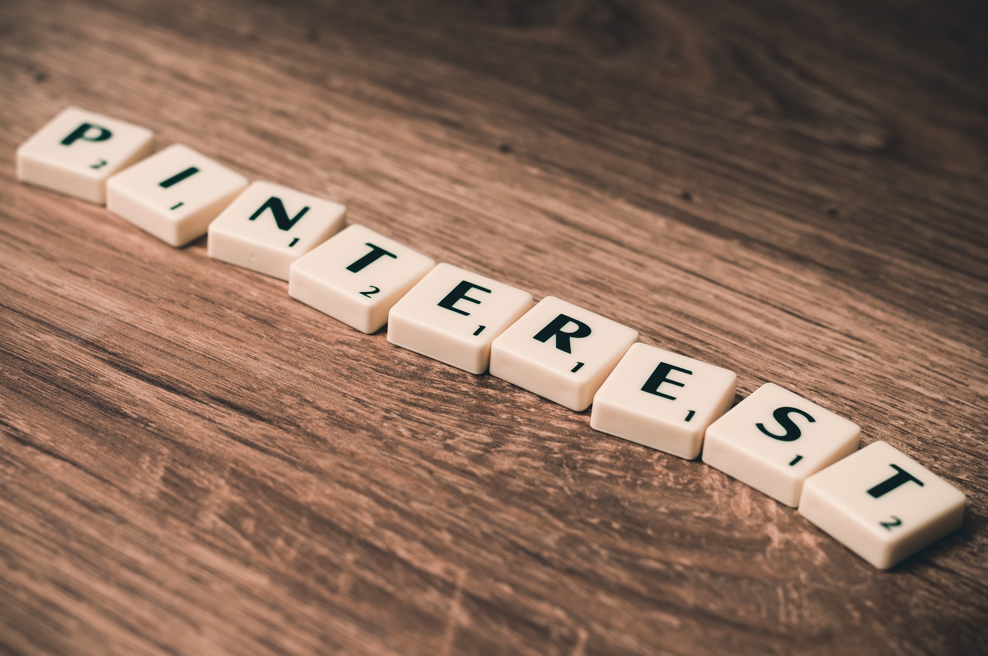 The word Pinterest spelt out in scrabble tiles on a wooden background to headline Using Pinterest in your Marketing Strategy